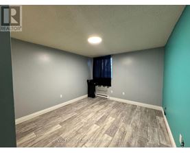 A room with a grey wall and a wooden floor.