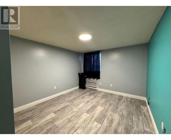 A room with a grey wall and a wooden floor.