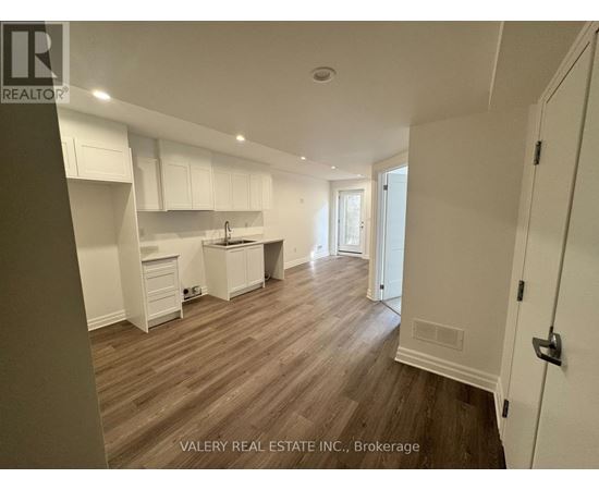 A kitchen with white cabinets and a wooden floor.