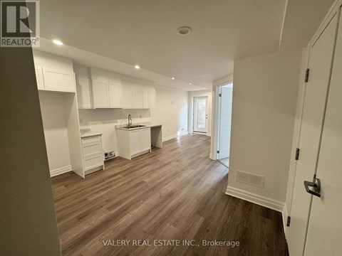 A kitchen with white cabinets and a wooden floor.