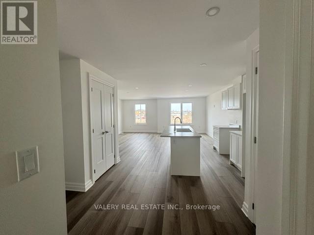 A spacious kitchen with wood flooring and white cabinetry.