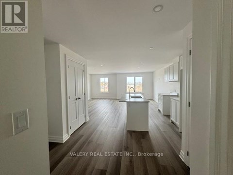 A spacious kitchen with wood flooring and white cabinetry.