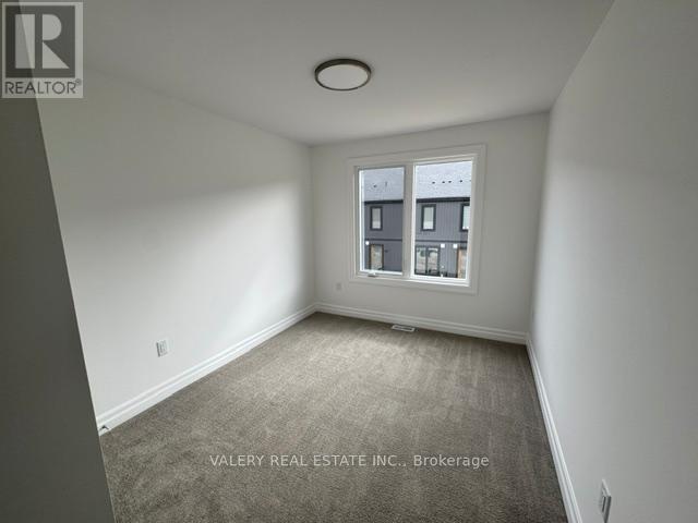 A room with a carpeted floor and a window showing a view of other buildings.