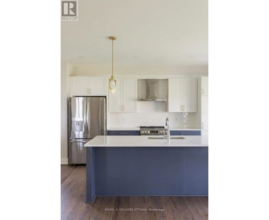 A kitchen with a stainless steel refrigerator and a sink with a countertop.