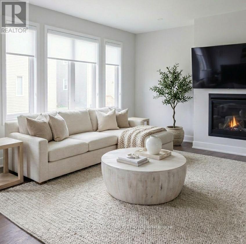 A living room with a white couch, a fireplace, and a flat screen TV mounted on the wall.