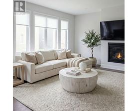 A living room with a white couch, a fireplace, and a flat screen TV mounted on the wall.