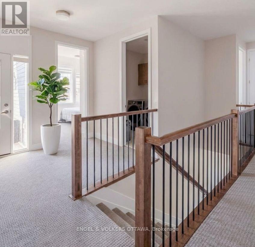 A well-lit, spacious hallway with a wooden railing and a potted plant.