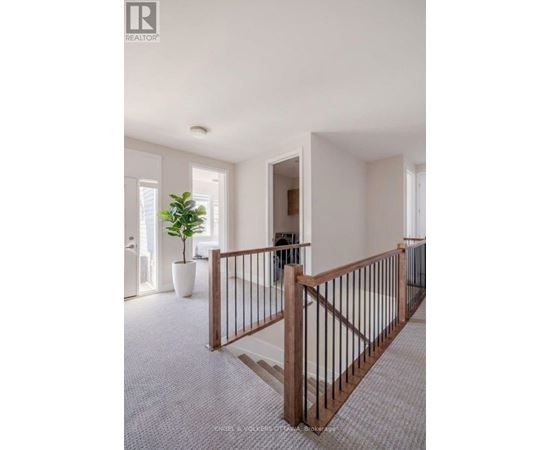 A well-lit, spacious hallway with a wooden railing and a potted plant.