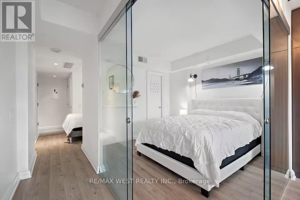 A bedroom with a bed, a nightstand, and a dresser with a mirror.