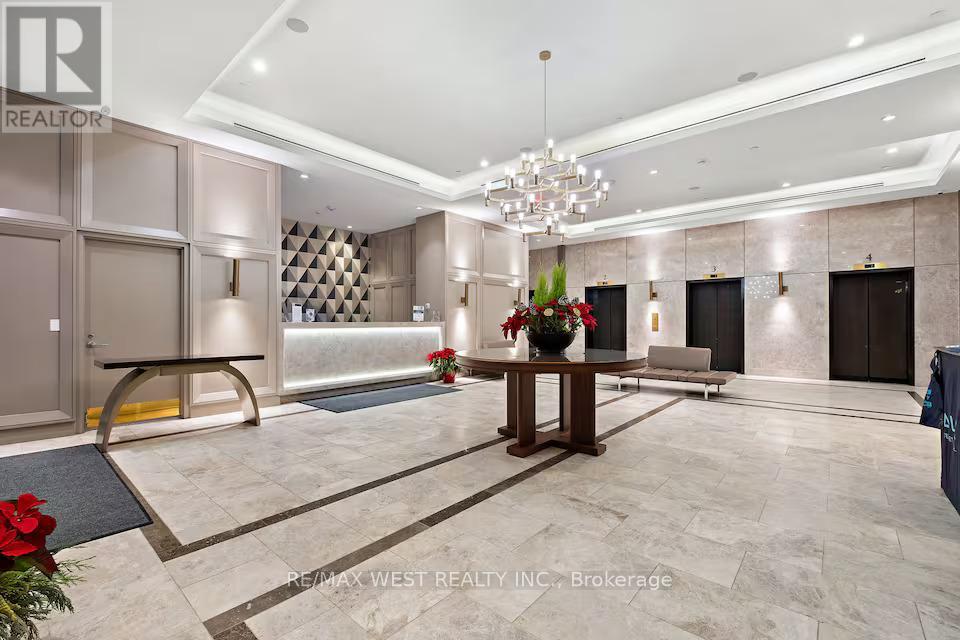 A well-lit, spacious lobby with a chandelier, a table with a vase of flowers, and a reception desk.