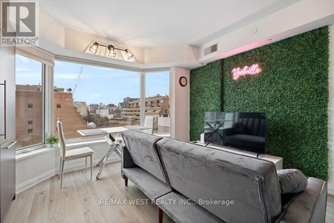 A living room with a grey couch and a green wall.