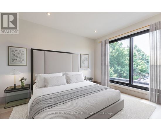 A bedroom with a large bed and a window overlooking a street.