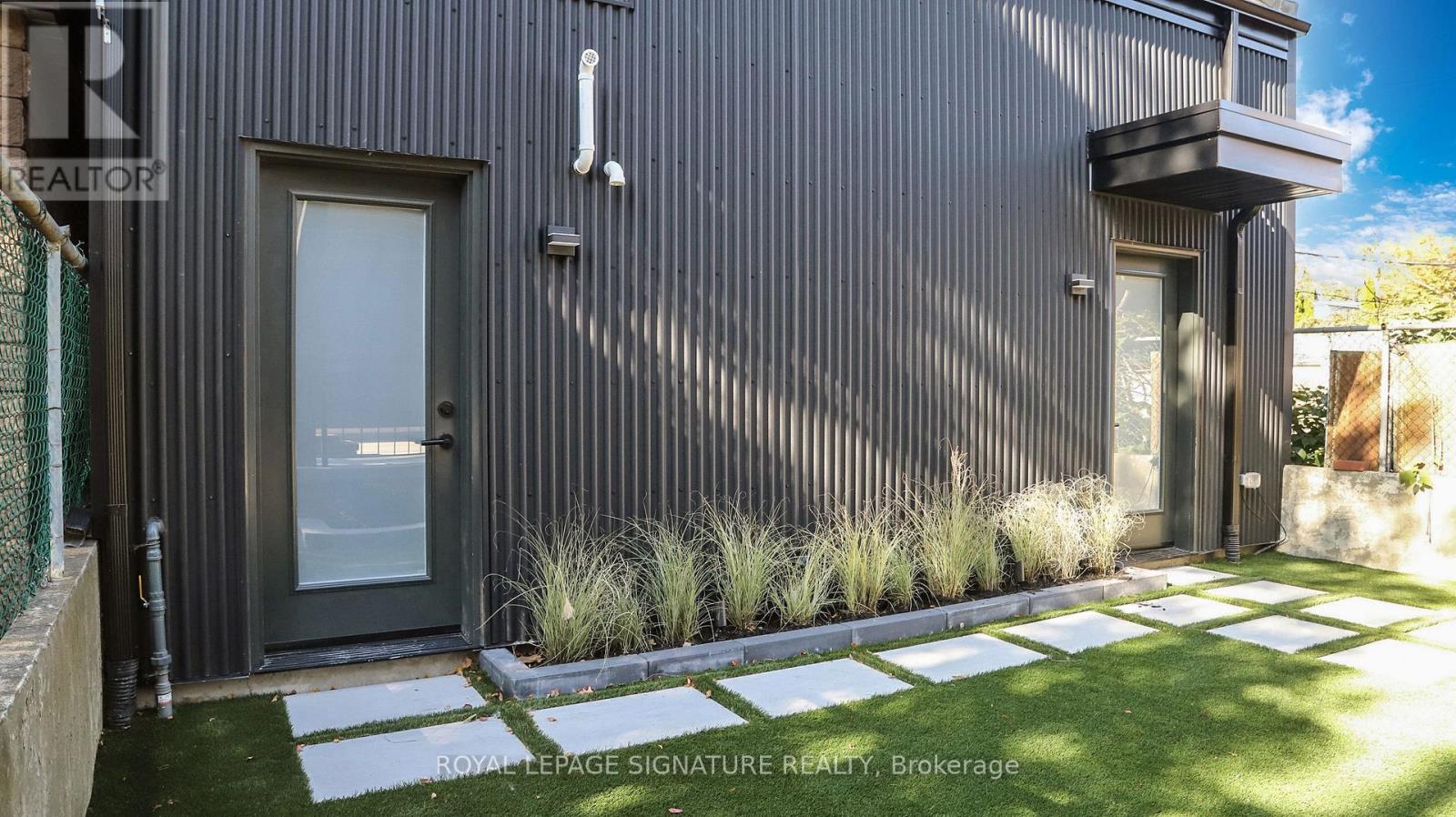 A modern house with a grey exterior and a glass door.