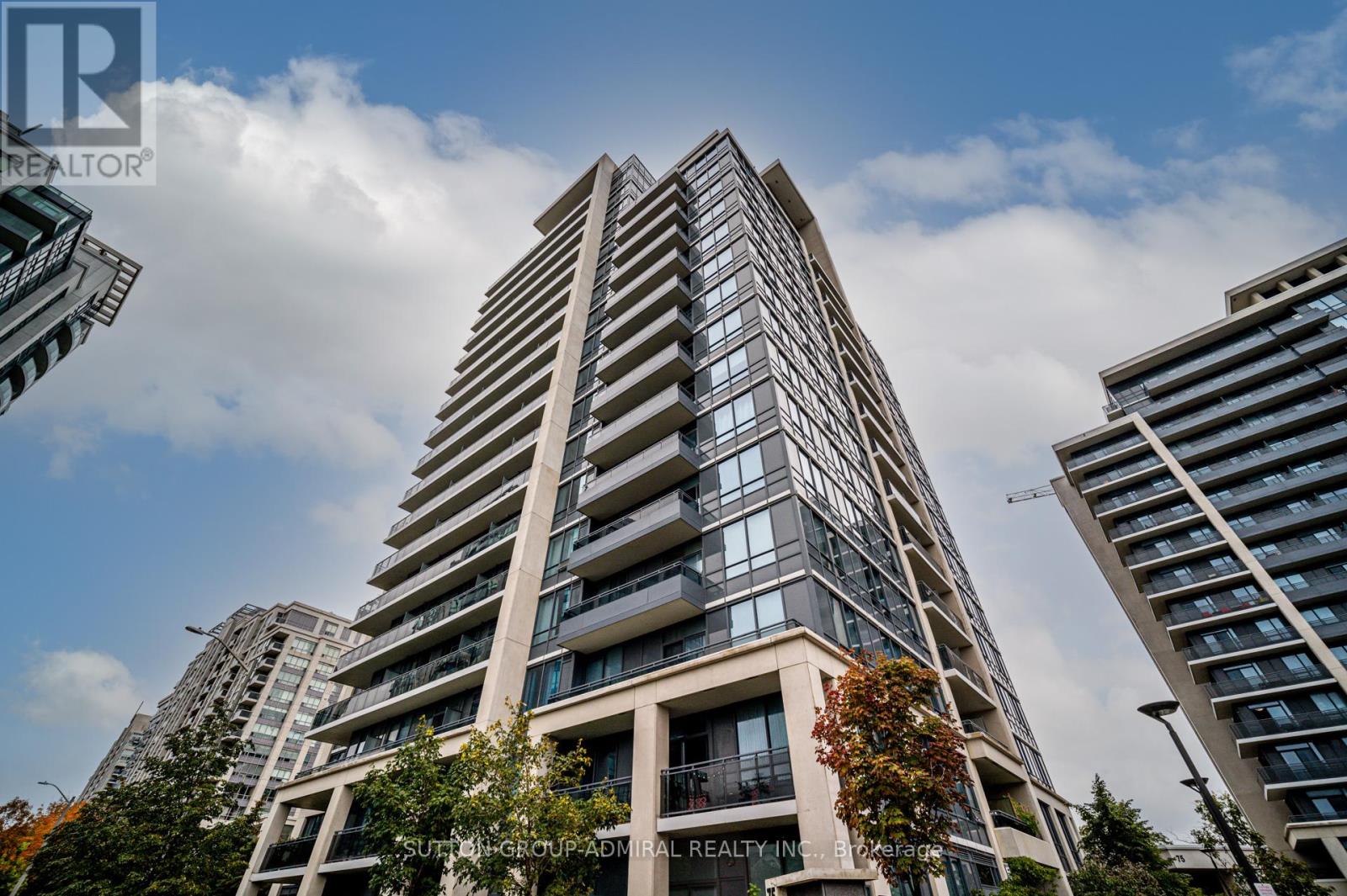 A tall residential building with balconies and a tree in front.