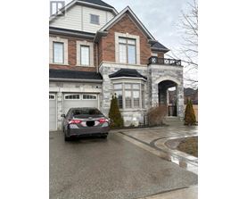 A black car is parked in front of a two-story house.