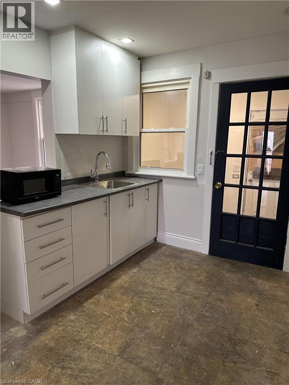 A kitchen with white cabinets and a black door.