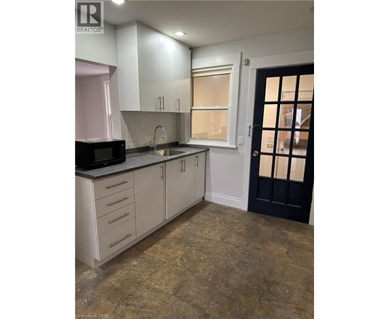 A kitchen with white cabinets and a black door.