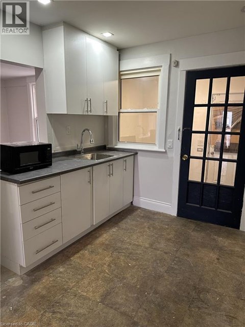 A kitchen with white cabinets and a black door.