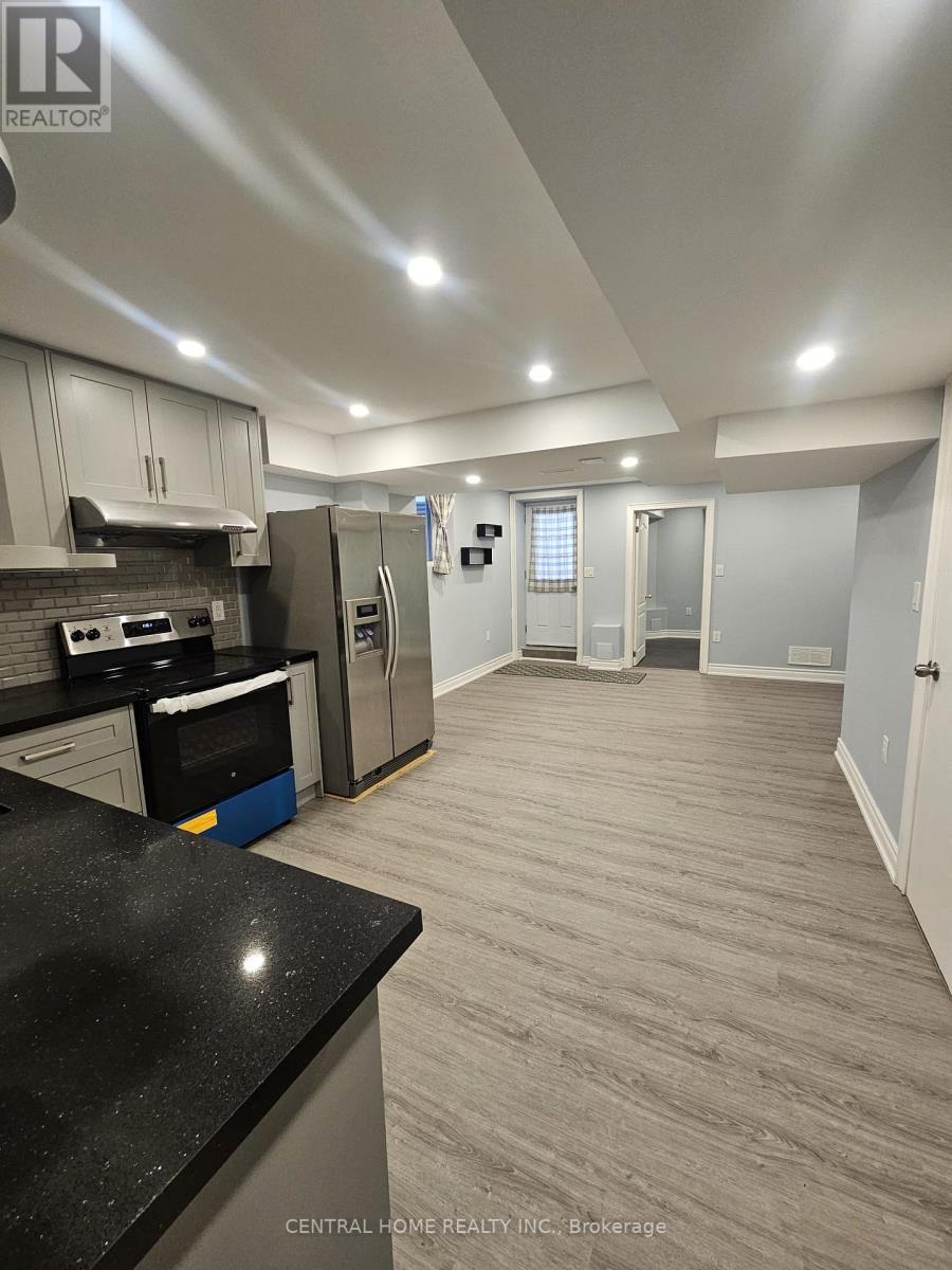 A kitchen with a black counter top and stainless steel appliances.