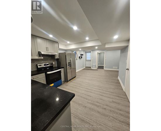 A kitchen with a black counter top and stainless steel appliances.
