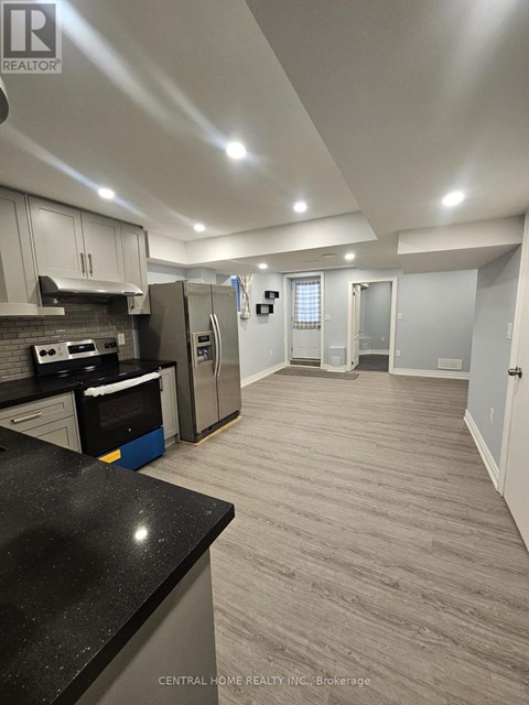 A kitchen with a black counter top and stainless steel appliances.