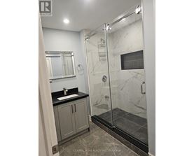 A bathroom with a walk in shower and a sink.