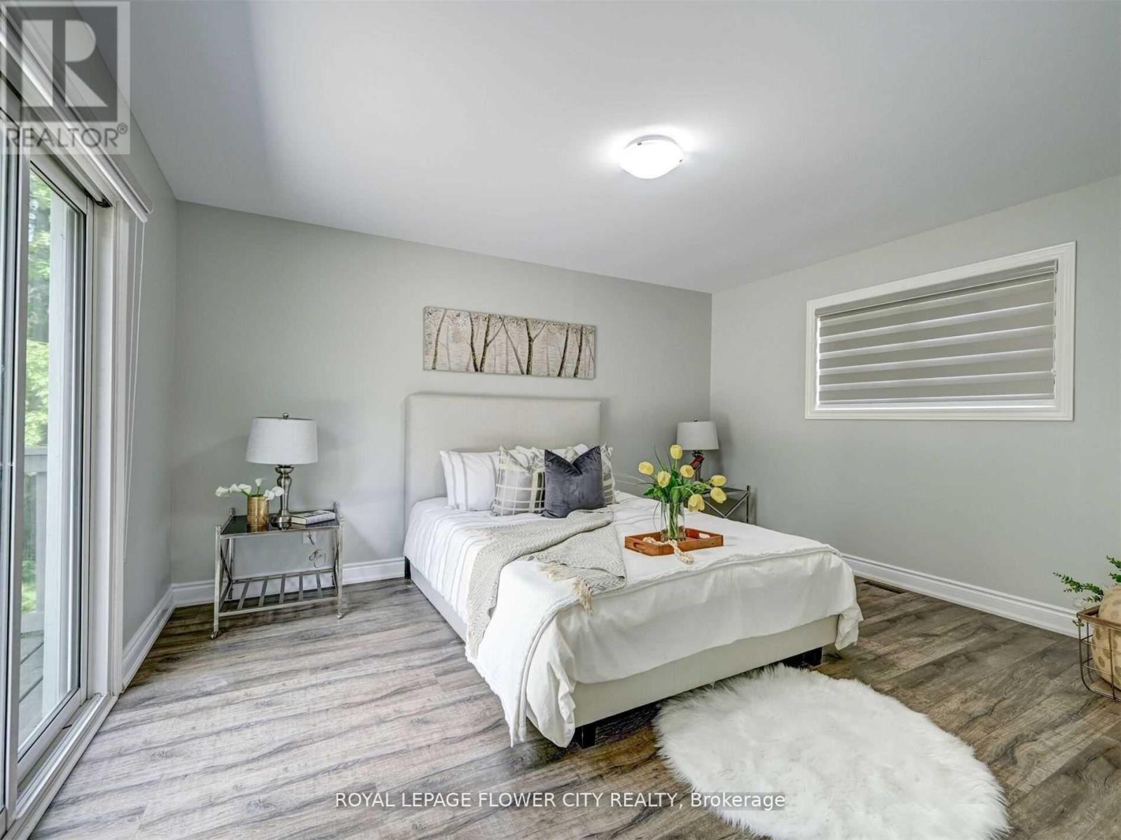 A bedroom with a large bed, a nightstand with a lamp, and a basket of flowers on the bed.