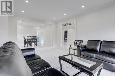 A black leather couch sits in a spacious living room with a glass coffee table.