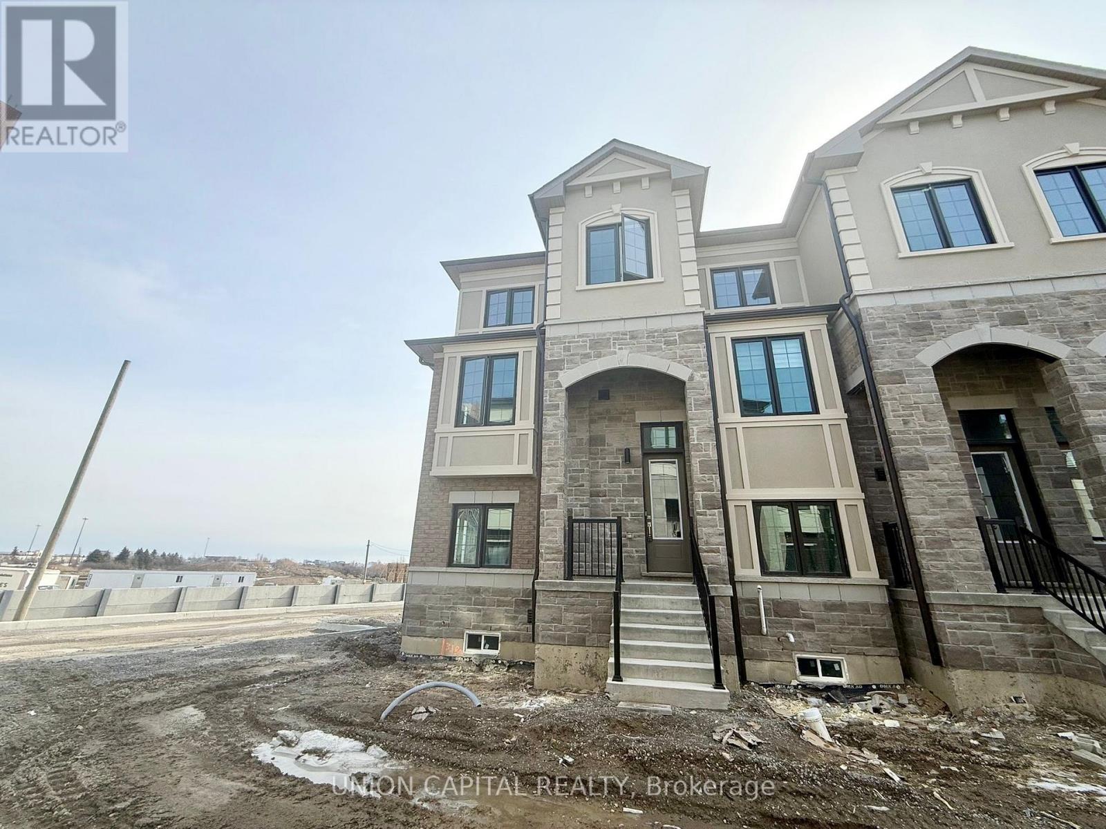 A large, two-story building with a stone facade and multiple windows is under construction.