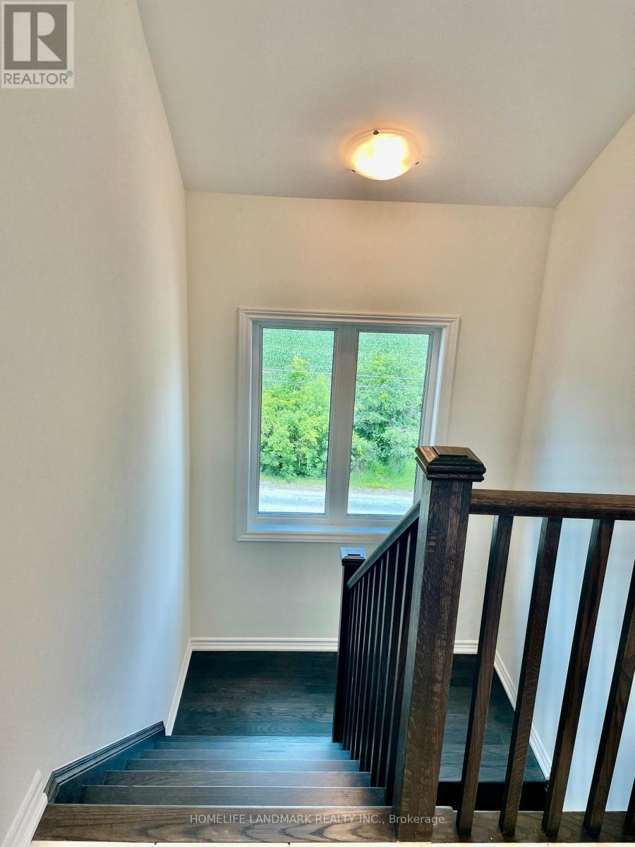A staircase with a wooden railing leads to a window with a view of greenery outside.