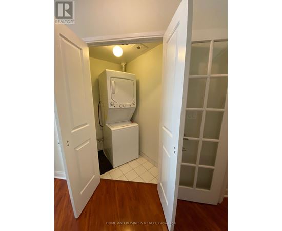 A white toilet is in a small room with a door open to a hallway.