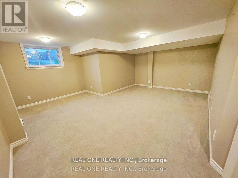 A spacious room with beige walls and carpet flooring, with a window and a skylight.