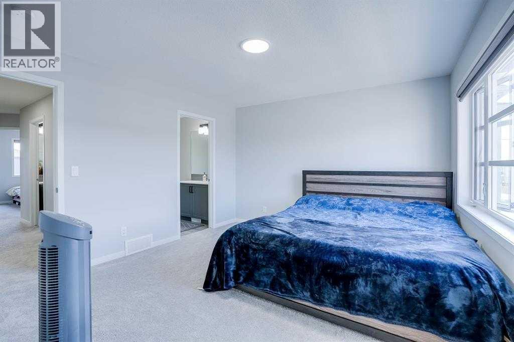 A bedroom with a blue bedspread and a bed with a white headboard.