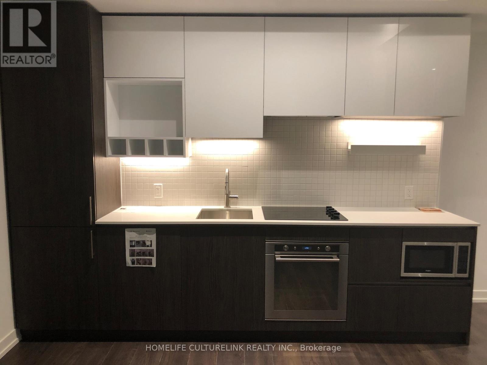 A modern kitchen with dark wood cabinets and stainless steel appliances.