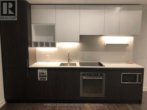 A modern kitchen with dark wood cabinets and stainless steel appliances.