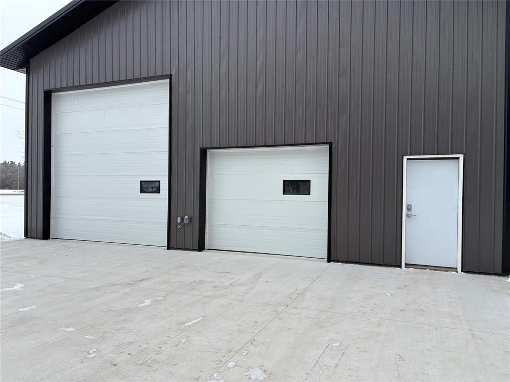 A building with three garage doors, two of which are white and one is black.
