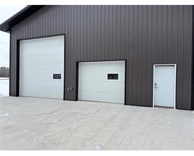 A building with three garage doors, two of which are white and one is black.