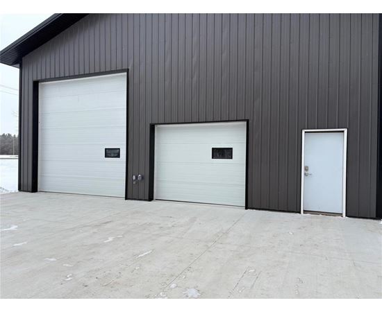 A building with three garage doors, two of which are white and one is black.