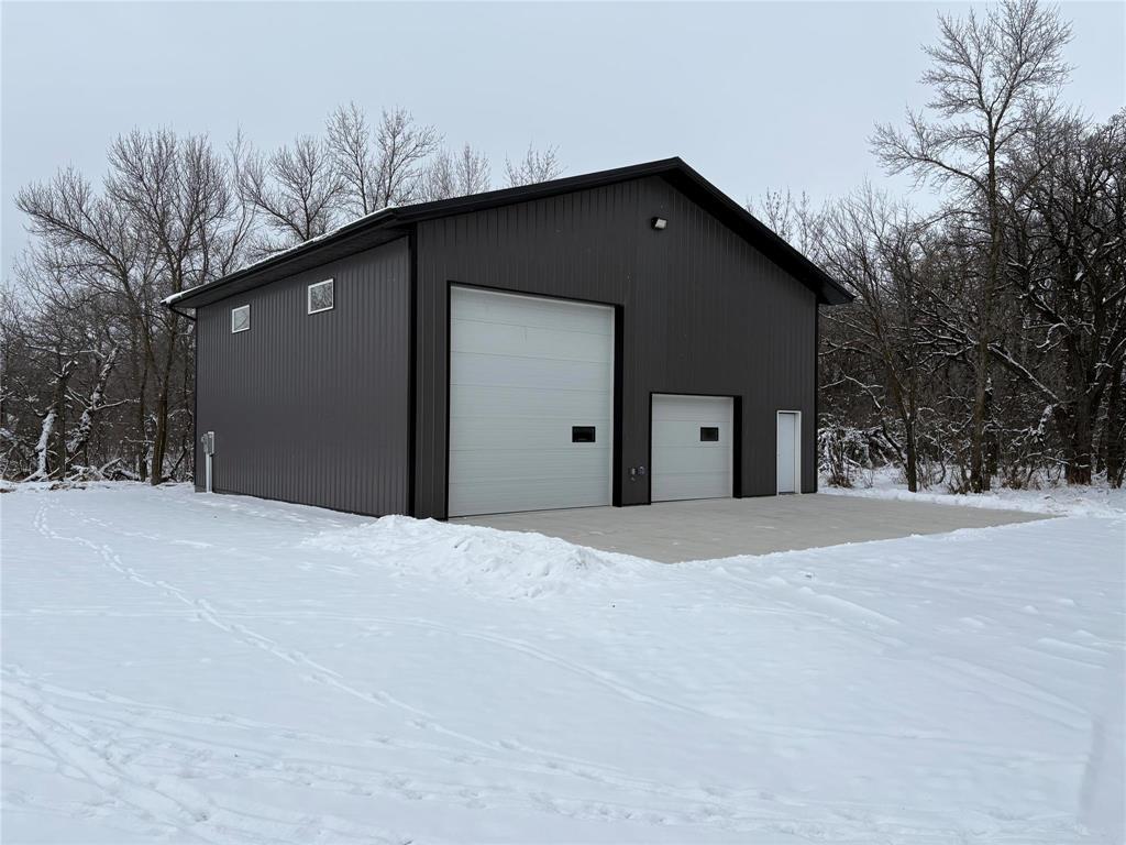 A black building with a white garage door sits in the snow.
