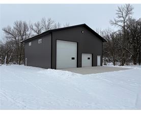 A black building with a white garage door sits in the snow.