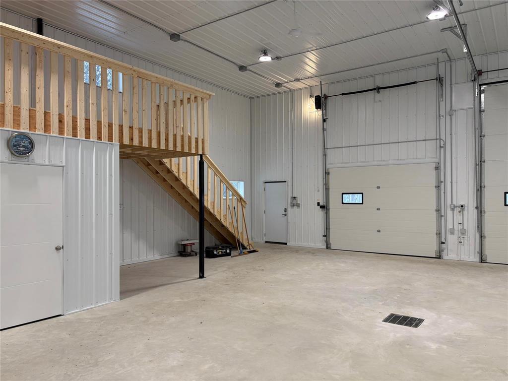 A spacious room with a staircase and a garage door.