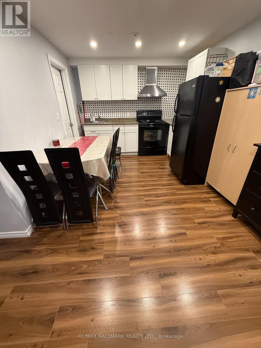 A kitchen with a table and chairs in the foreground and a refrigerator and oven in the background.