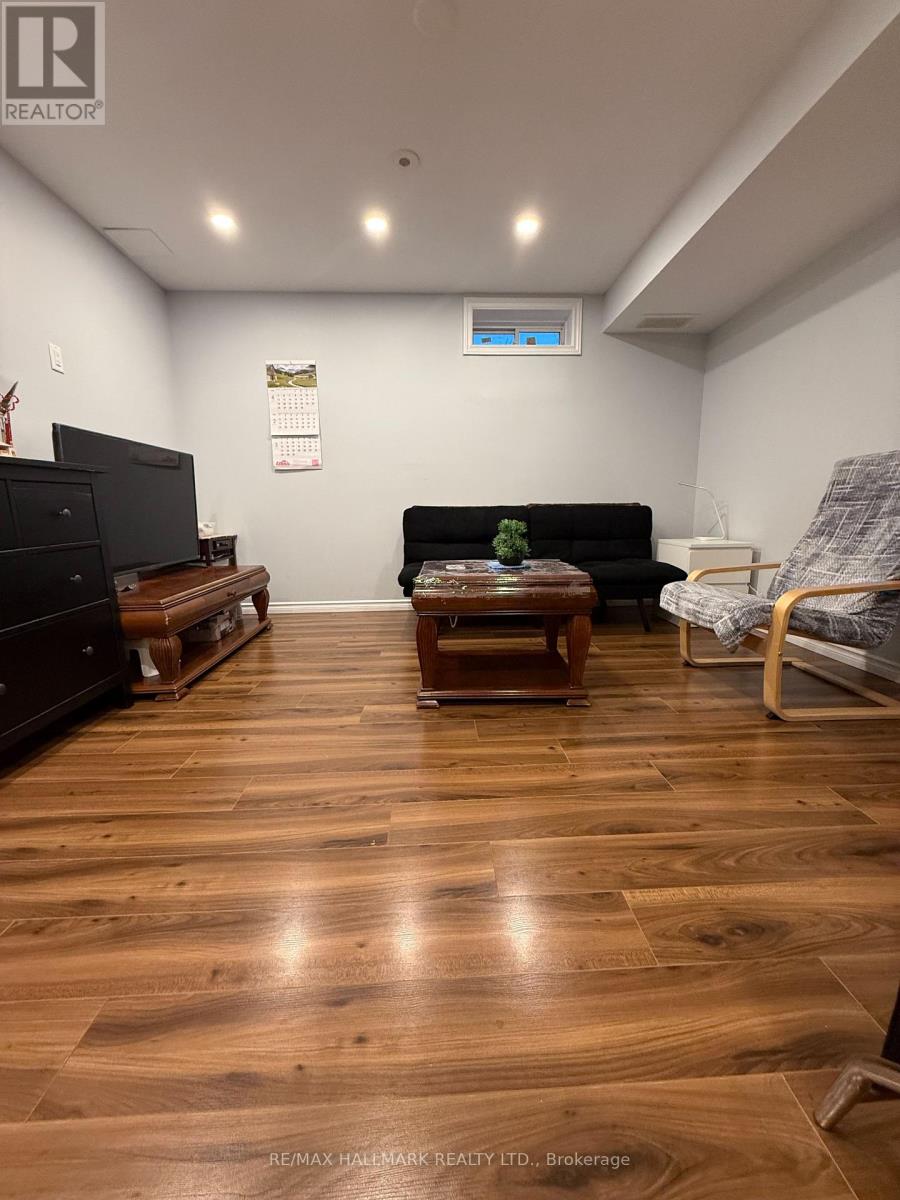 A living room with a black couch and wooden floors.