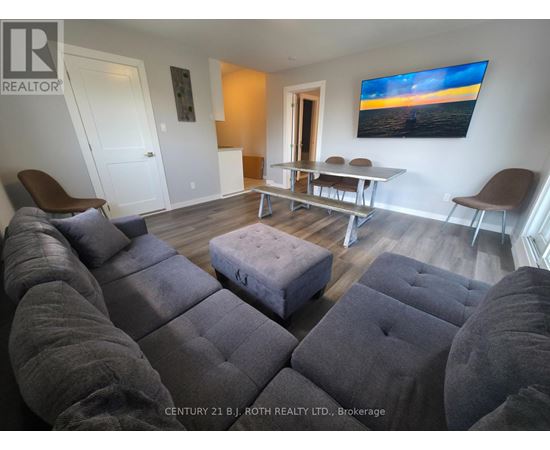 A living room with grey couches and a painting on the wall.