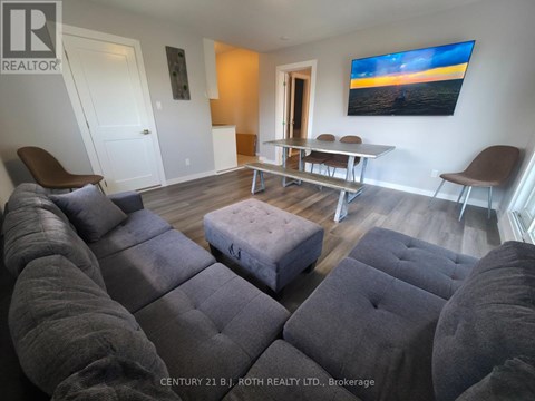A living room with grey couches and a painting on the wall.