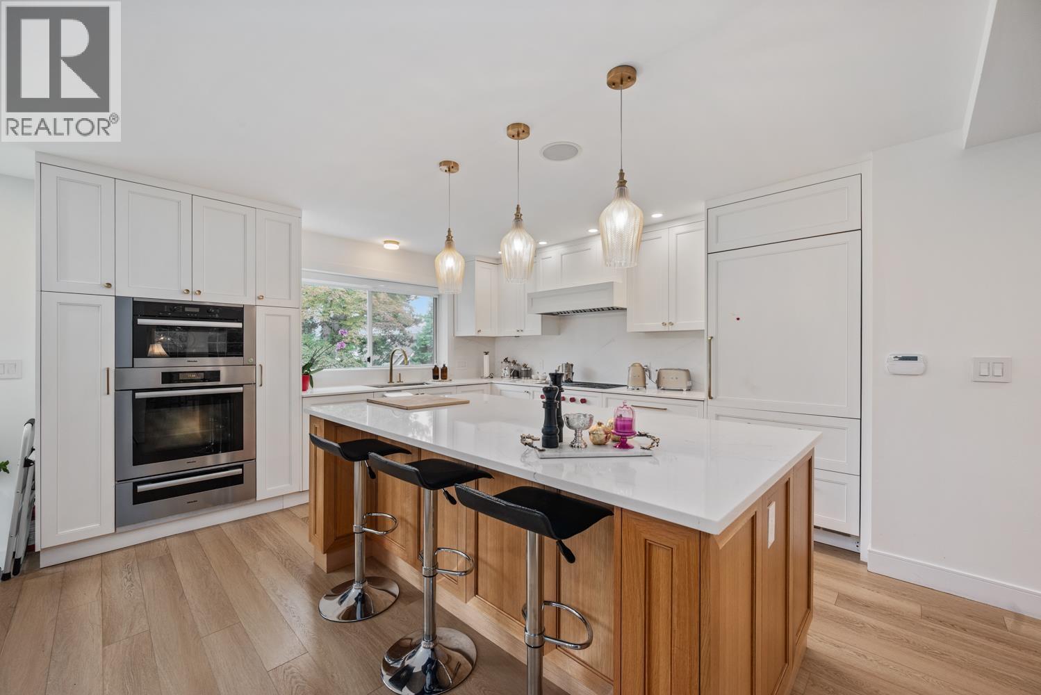 A modern kitchen with a white countertop and wooden cabinets.