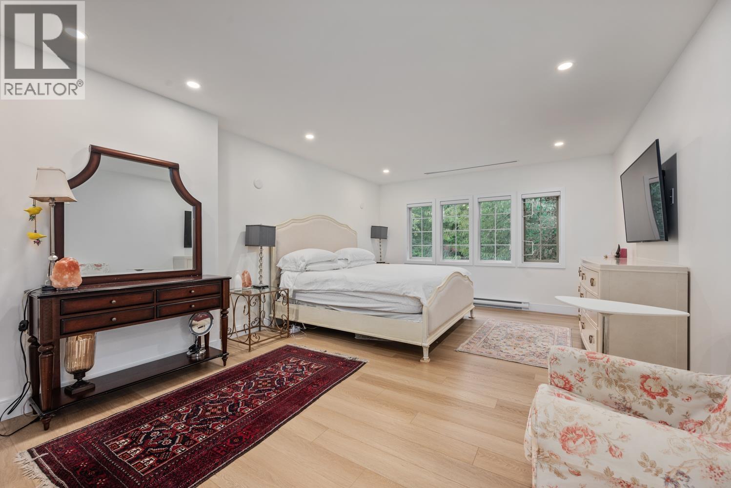 A bedroom with a large bed, a dresser, and a chair.