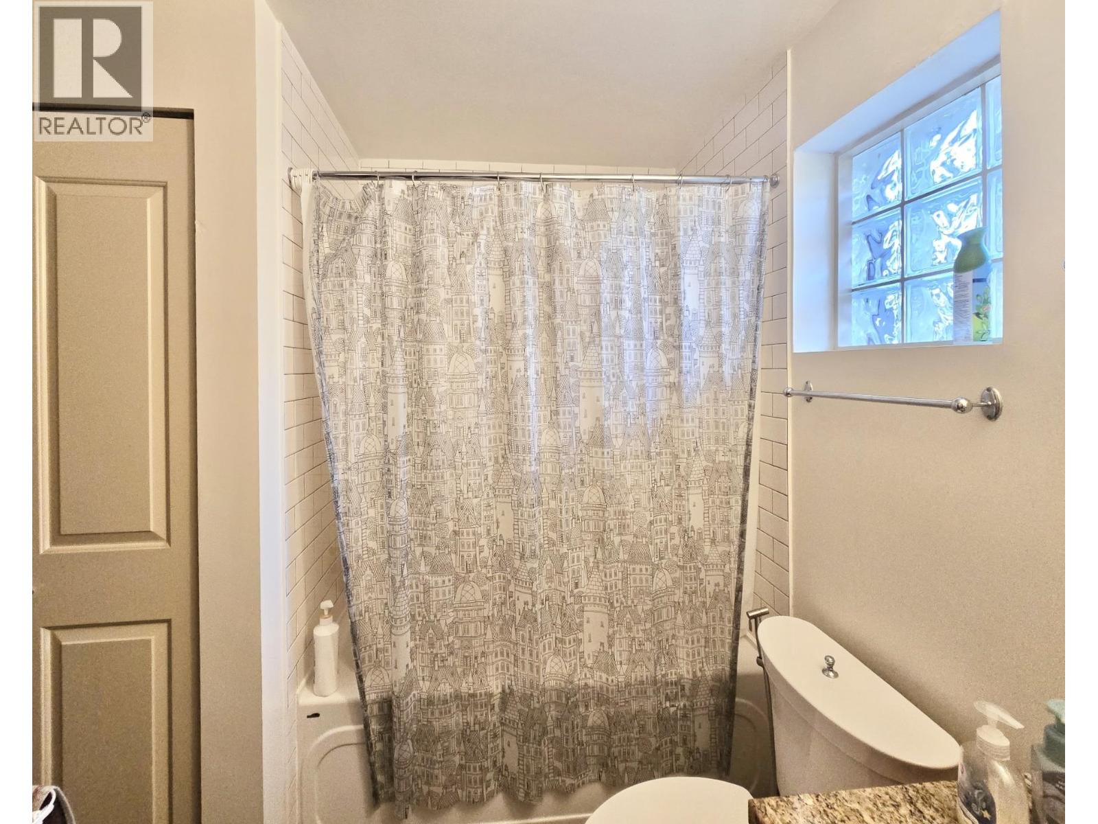 A bathroom with a shower curtain and a toilet.