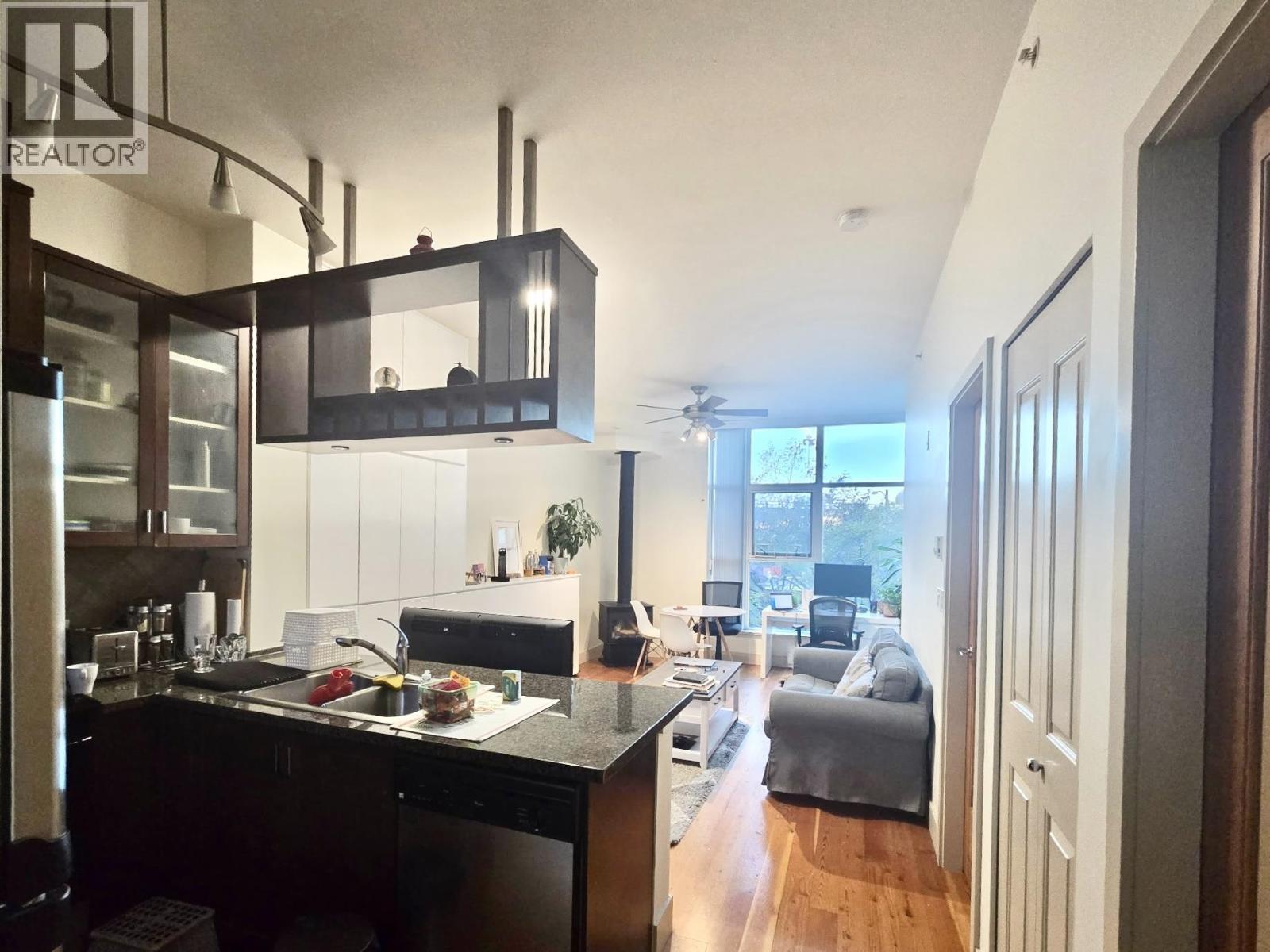 A modern kitchen with dark wood cabinets and a black countertop.