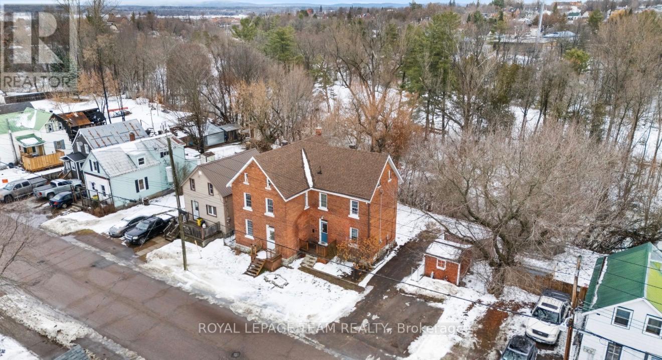 A red brick house with a brown roof in the middle of a snowy street.